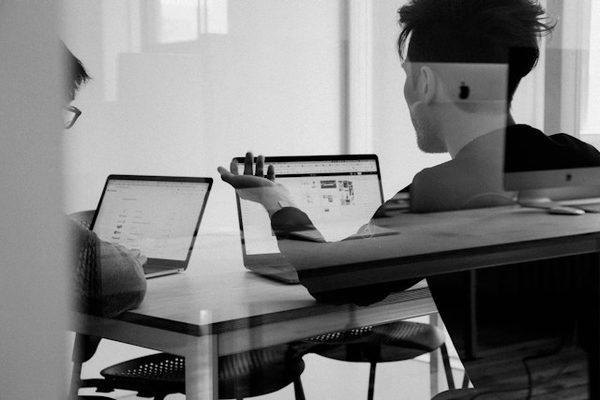 Duas pessoas conversando diante de notebooks, durante a abertura de uma empresa
