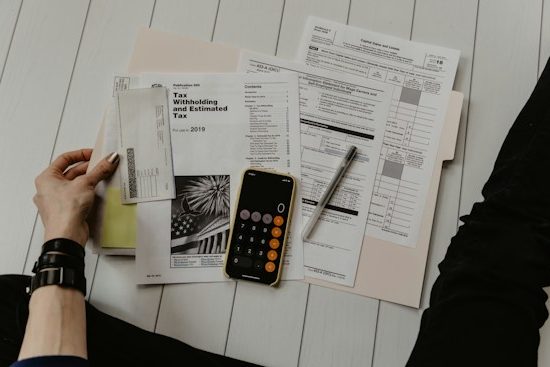 Documentos fiscais, calculadora e celular organizados sobre a mesa